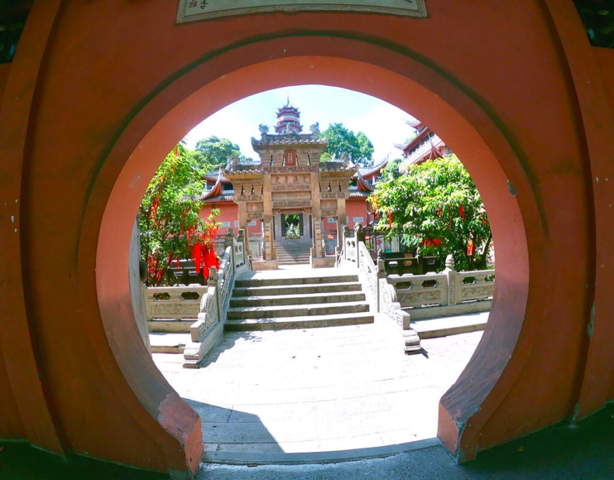 Exploring Huayan Temple. Picture shows a circular entrance with a traditional Chinese-like temple behind and stairs. One of the best things to do in Chongqing