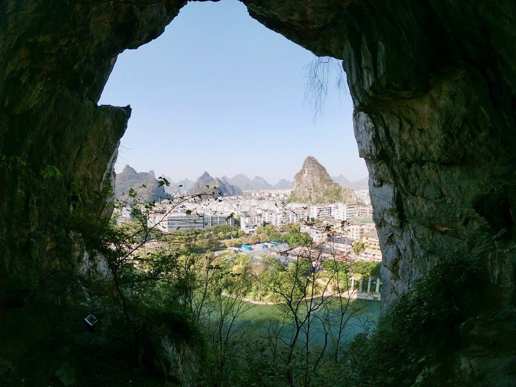 The city of Guilin and some hills seen through a large karst cave while hiking in Guilin