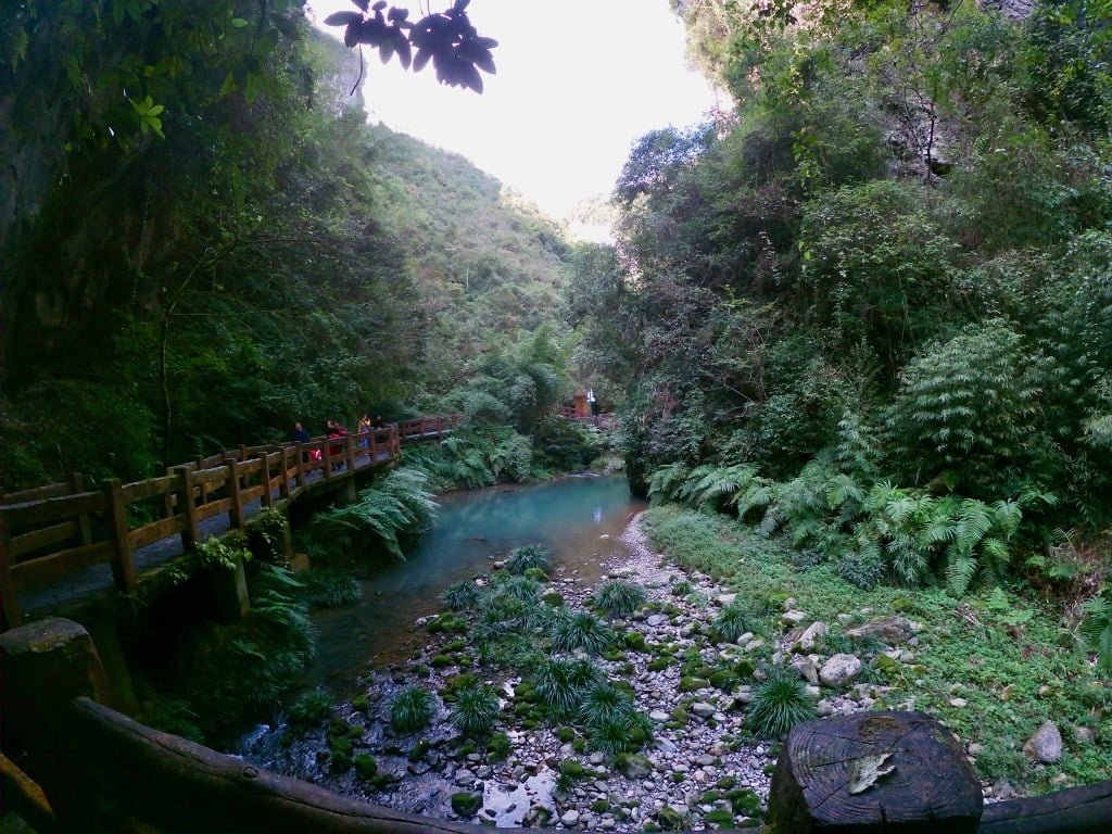Longshuixia Gorge in Wulong, featuring turquoise water, lush greenery, and a narrow pathway: a good attraction to pair with the 3 Natural Bridges