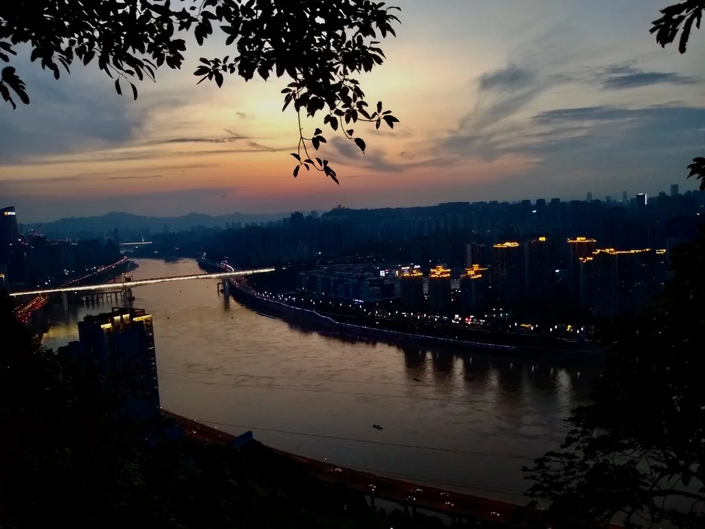 A picture of Chongqing from Eling Park during the day, showing the river, forests, and many apartments buildings - a top travel location in Chongqing