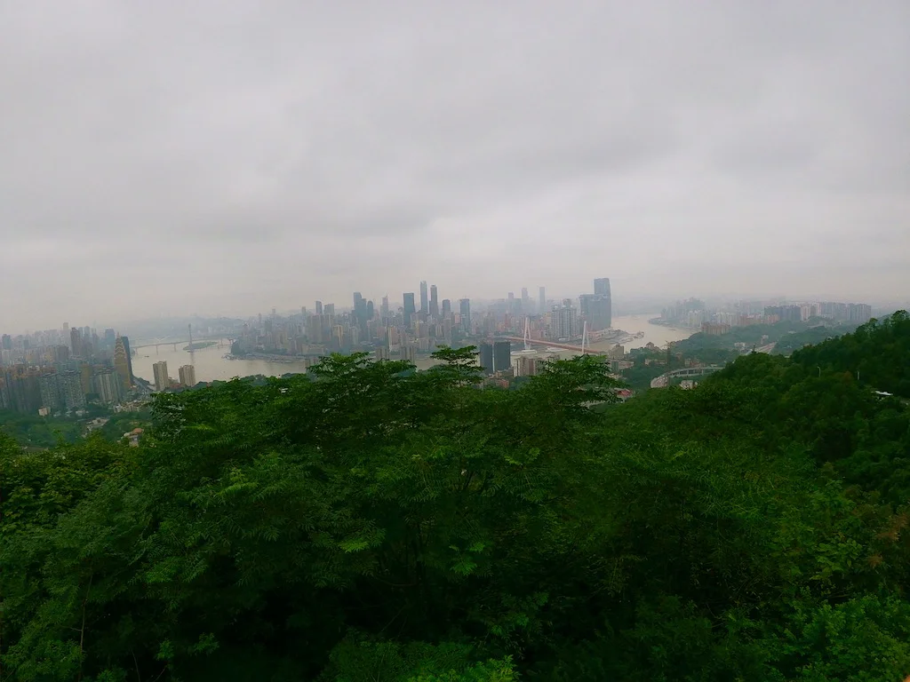 Nanshan mountain in Chongqing, showing the convergence of the two rivers, green foliage, and apartment buildings