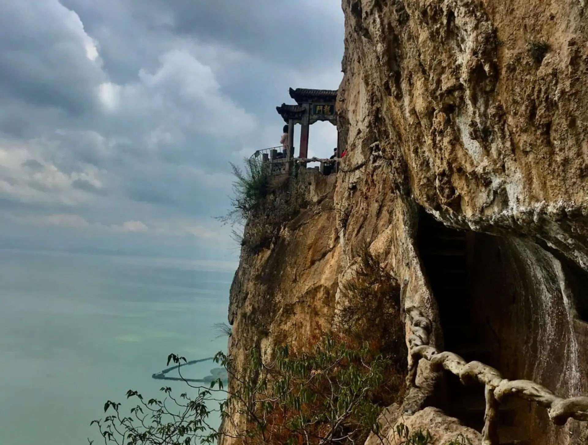 Xishan mountain in Kunming, China; a gate on the side of a cliff overlooking a large lake
