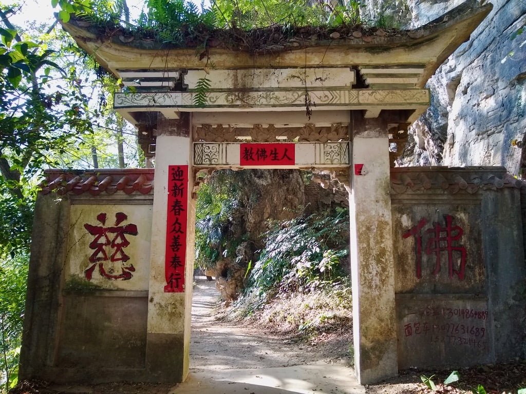 A Chinese-style gate, white with red writing of characters, showing the entrance to a nunnery in Xingping, China. 
