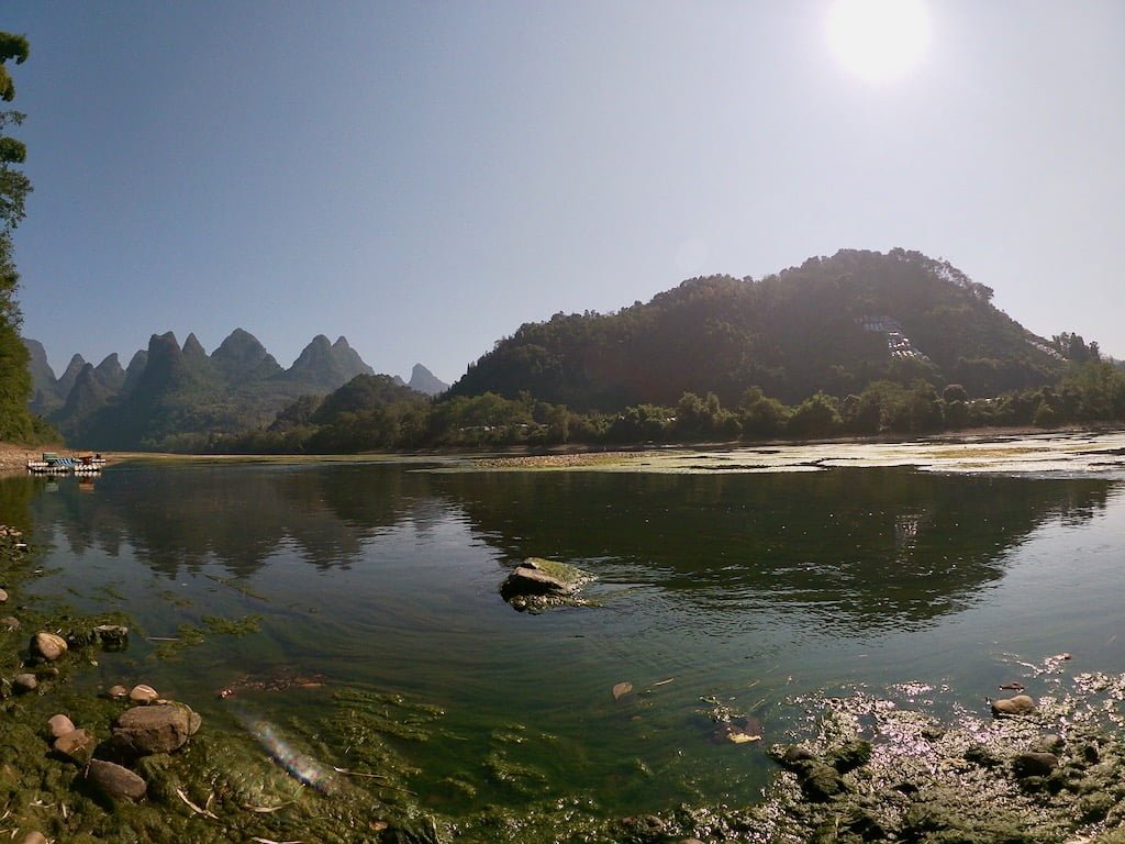 The river, with karst hills in the background, located in Shawan, accessible by hike from Xingping.