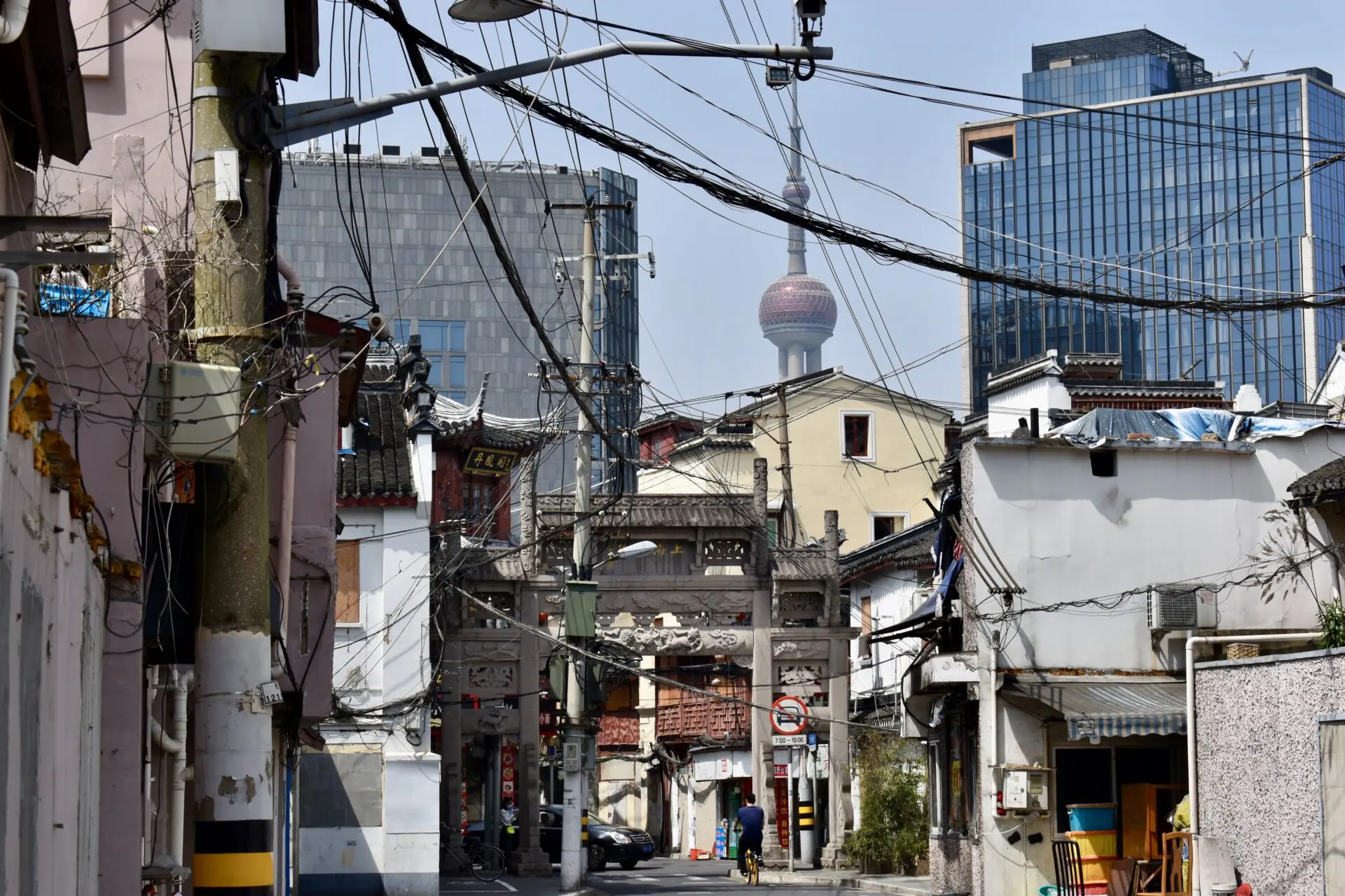Forced to wrong size: 451x301, natural is 1920x1280! A view of Shanghai city, with traditional buildings on the sides, lots of cable wires, and skyline buildings in the background.
